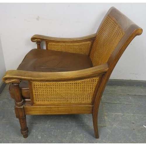 702 - An antique style fruitwood armchair, having double skin bergère back and sides, with loose cushions ... 