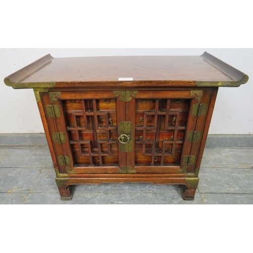 708 - An antique Chinese elm apothecary cabinet with brass mounts, the tracery doors opening onto a select... 