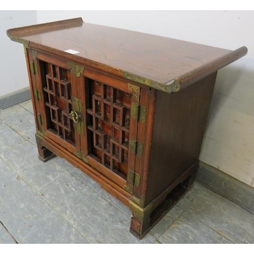 708 - An antique Chinese elm apothecary cabinet with brass mounts, the tracery doors opening onto a select... 