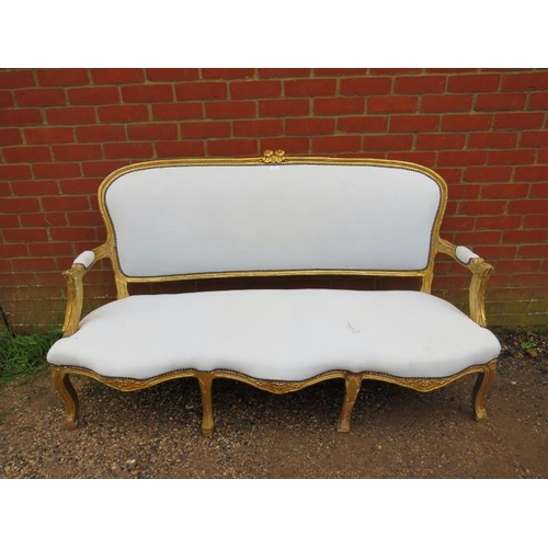 716 - A 19th century French giltwood three-seater sofa, having a serpentine front, reupholstered in calico... 