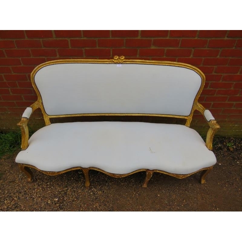 716 - A 19th century French giltwood three-seater sofa, having a serpentine front, reupholstered in calico... 