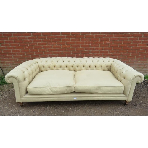 719 - An antique three-seater Chesterfield sofa, reupholstered in neutral buttoned material, on fluted gil... 