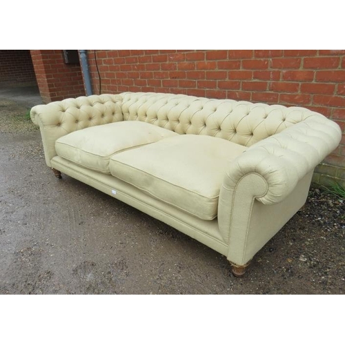 719 - An antique three-seater Chesterfield sofa, reupholstered in neutral buttoned material, on fluted gil... 