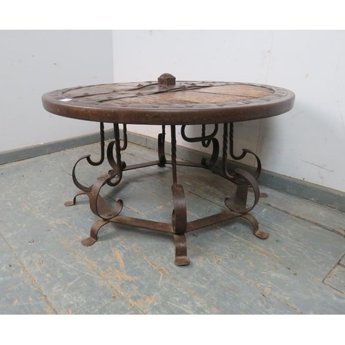 721 - A low circular coffee table fashioned from a medieval cartwheel with iron strapwork mounts, on a bes... 