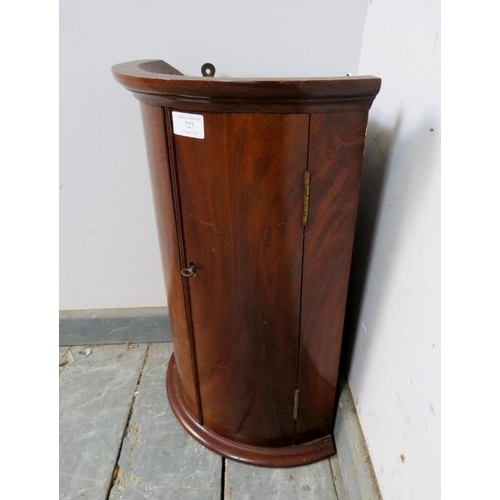 727 - A George III flame mahogany bow-fronted hanging corner cupboard of diminutive proportions, having a ... 