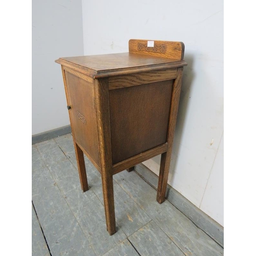 755 - An Art Deco Period medium oak bedside cabinet, with applied decoration and bakelite handle, on reede... 