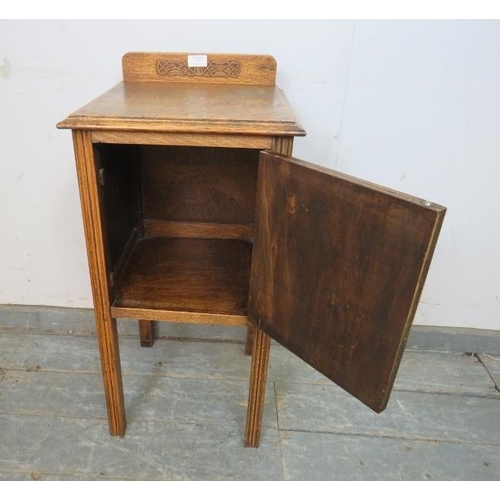 755 - An Art Deco Period medium oak bedside cabinet, with applied decoration and bakelite handle, on reede... 