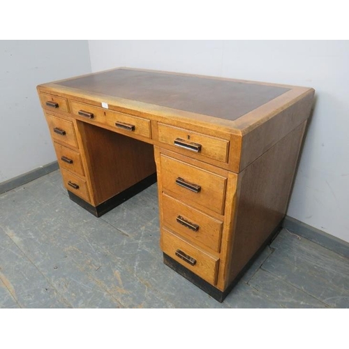 757 - An Art Deco Period light oak pedestal desk, housing a configuration of nine graduated drawers with e... 