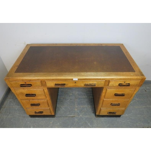 757 - An Art Deco Period light oak pedestal desk, housing a configuration of nine graduated drawers with e... 