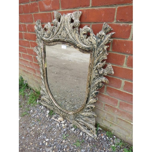 763 - A 19th century shield-shaped wall mirror, within an ornate carved wooden surround depicting thistle ... 