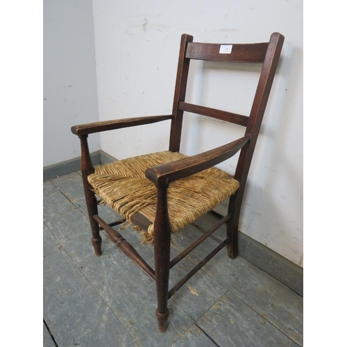 769 - An antique fruitwood child’s elbow chair with rush seat, on turned supports with stretchers. 
H68cm ... 