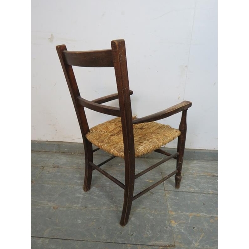 769 - An antique fruitwood child’s elbow chair with rush seat, on turned supports with stretchers. 
H68cm ... 