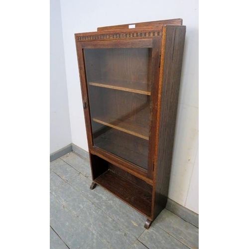 782 - An antique oak narrow bookcase, the glazed door opening onto two fitted shelves with open shelf unde... 