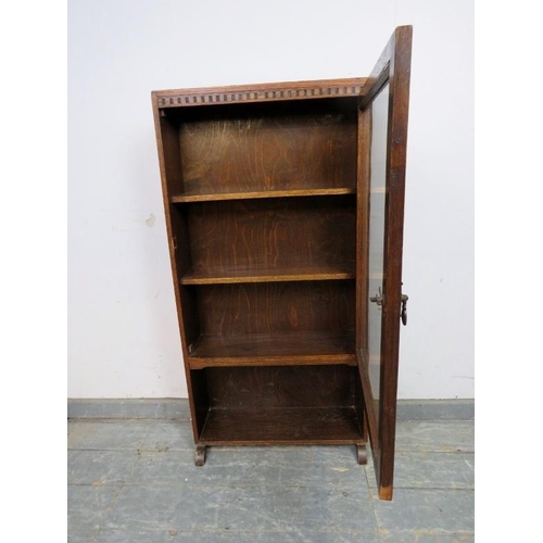 782 - An antique oak narrow bookcase, the glazed door opening onto two fitted shelves with open shelf unde... 