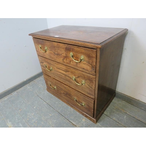 783 - An antique elm chest, housing three graduated long drawers with brass bail handles, on a plinth base... 