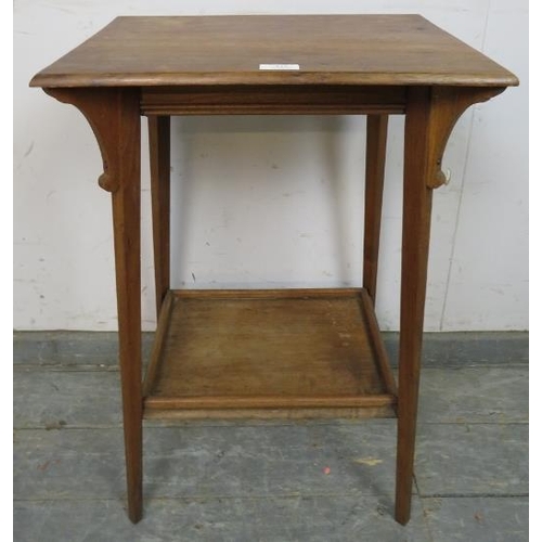 815 - An Arts & Crafts walnut two-tier occasional table, having shaped corner brackets, on canted tapering... 