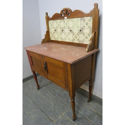 827 - A turn of the century walnut washstand, the rear gallery with inset tiles, above a rouge marble top,... 