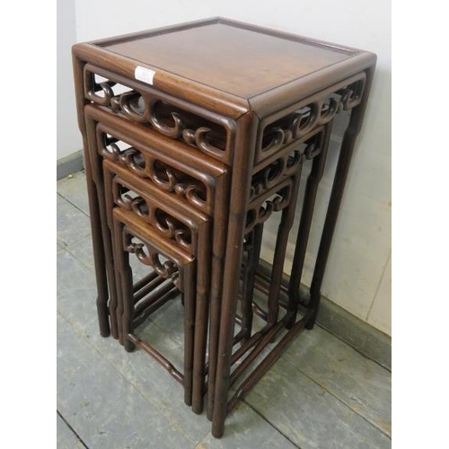 864 - A vintage Chinese hardwood nest of four graduated tables, having carved and pierced frieze decoratio... 