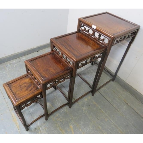 864 - A vintage Chinese hardwood nest of four graduated tables, having carved and pierced frieze decoratio... 