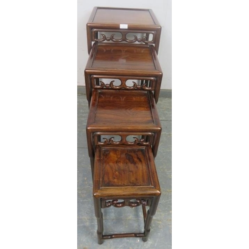 864 - A vintage Chinese hardwood nest of four graduated tables, having carved and pierced frieze decoratio... 