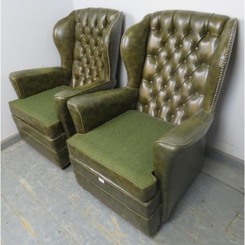 867 - A pair of vintage Chesterfield style wingback armchairs, upholstered in faux green leather with bras... 