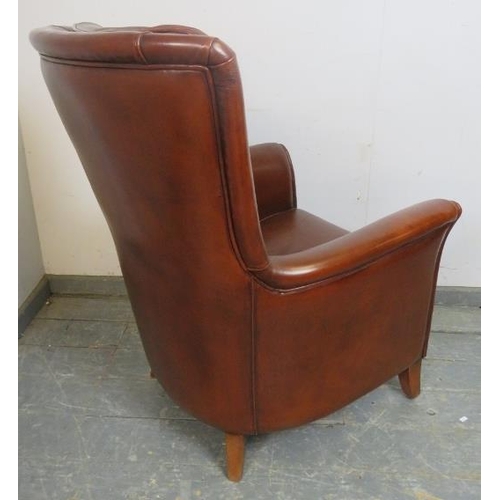 872 - A contemporary armchair, upholstered in tobacco brown leather, on sabre legs. 
H98cm W72cm D76cm (ap... 