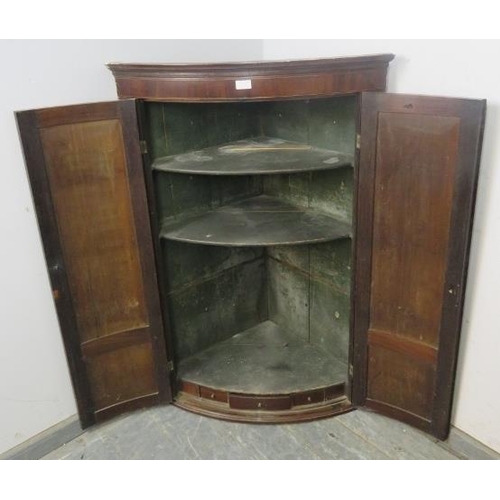 878 - A George III flame mahogany bow-fronted hanging corner cupboard with ebony and boxwood inlay, the pa... 