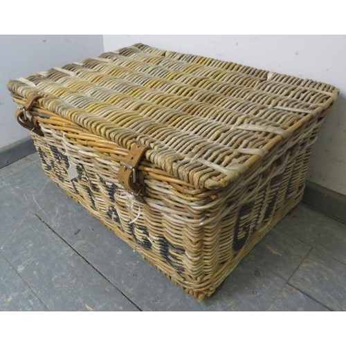 883 - An antique wicker laundry basket, with handles to either side and leather fastening straps, emblazon... 