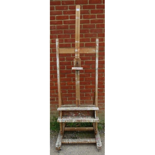 887 - A vintage beech height adjustable artist’s easel with brass fittings, on rail supports with castors.... 