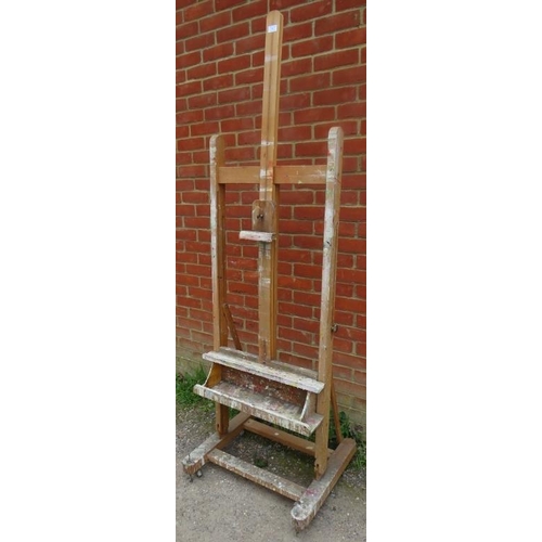 887 - A vintage beech height adjustable artist’s easel with brass fittings, on rail supports with castors.... 