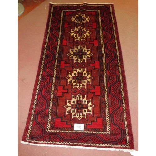 902 - North East Persian Meshed Belouch rug, five central repeat motifs, cream on red ground. 235cm x 116c... 