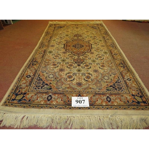 907 - A Persian design rug, central motif, surrounded by repeat fawn, cream & brown. 176cm x 94cm (approx)... 