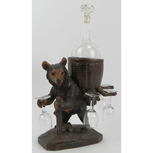 101 - A Black Forest carved wood bear drinks decanter set. Modelled depicting a hiking bear carrying a bas... 