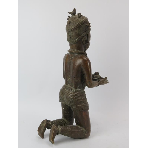 260 - Tribal Art: An African Benin style cast bronze kneeling figure offering cocoa beans. 46.5 cm height.... 