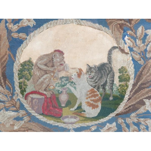 284C - A Victorian needlework tapestry. Decorated with an oval scene depicting two cats and a monkey in a g... 