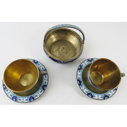 328 - Two Russian silver gilt and enamel cups and saucers and a matching sugar basket.  Each with enamelle... 