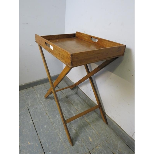 711 - An early 20th century walnut butler’s tray on stand, the galleried tray with pierced handles to eith... 