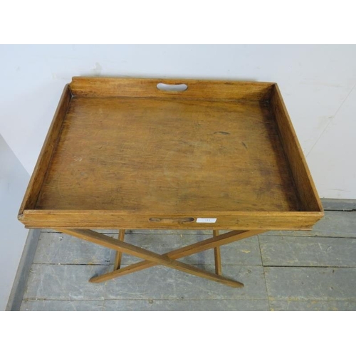 711 - An early 20th century walnut butler’s tray on stand, the galleried tray with pierced handles to eith... 