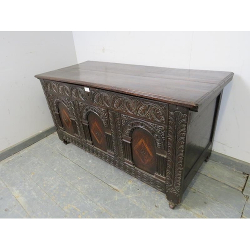 713 - A late 17/early 18th century oak panelled coffer, having internal candle box, the front profusely ca... 