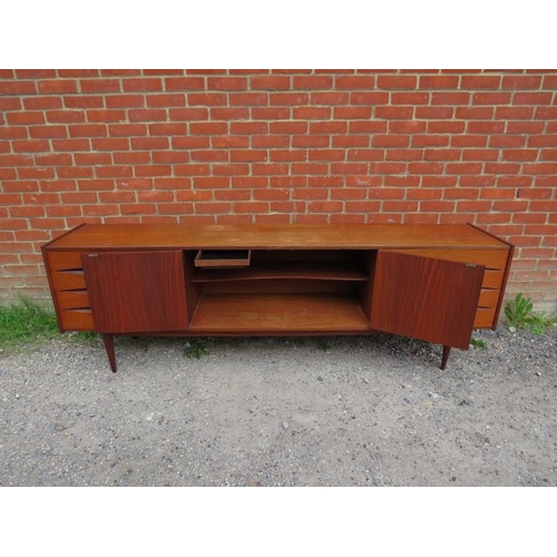 717 - A mid-century Danish teak sideboard, the double doors with turned wooden handles, opening onto a hei... 