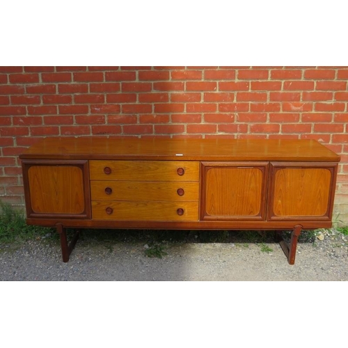 718 - A mid-century teak sideboard, having three short drawers with turned wooden handles, flanked by cupb... 