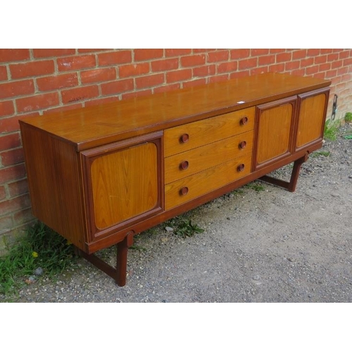 718 - A mid-century teak sideboard, having three short drawers with turned wooden handles, flanked by cupb... 