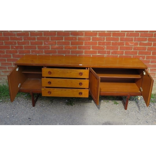 718 - A mid-century teak sideboard, having three short drawers with turned wooden handles, flanked by cupb... 