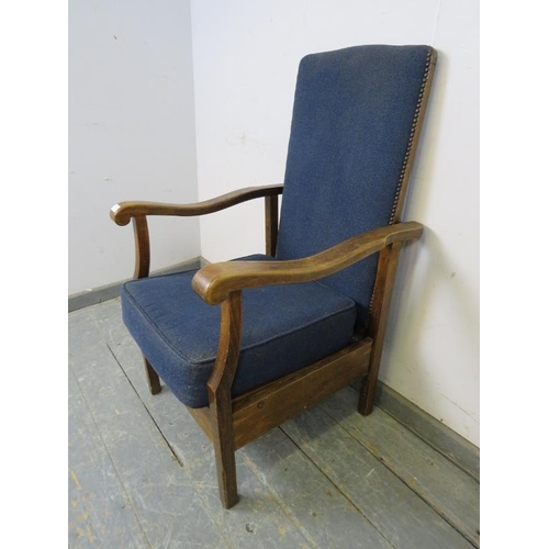 742 - A 1920s oak reclining open-sided armchair, upholstered in navy material with brass studs, the shaped... 