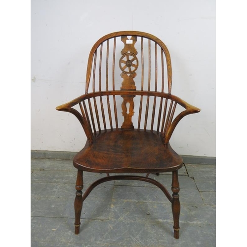 749 - An ash Windsor wheelback chair in the 19th century taste, having carved and pierced back splat, join... 