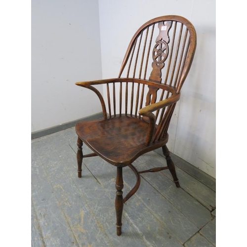 749 - An ash Windsor wheelback chair in the 19th century taste, having carved and pierced back splat, join... 