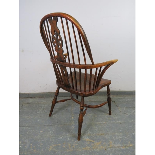 749 - An ash Windsor wheelback chair in the 19th century taste, having carved and pierced back splat, join... 