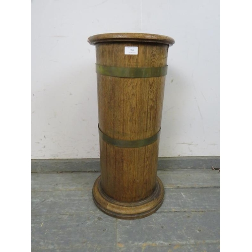 764 - An early 20th century coopered light oak cylinder stick stand, having a tin liner, on a plinth base.... 