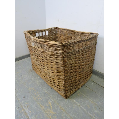 775 - A large vintage woven willow log basket, with pierced handles to either side.
H62cm W84cm D67cm (app... 