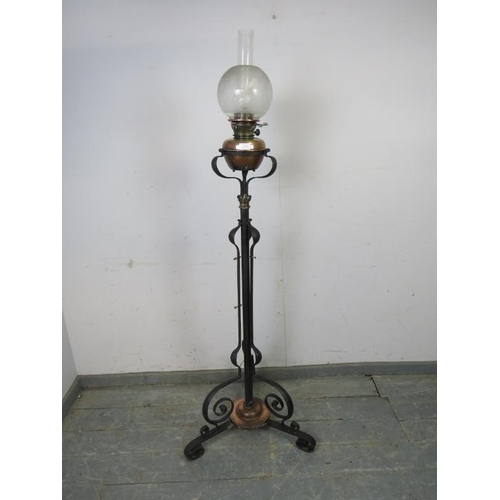 784 - An Art Nouveau floor-standing wrought iron and copper oil lamp, on scrolled tripod supports. 
H165cm... 